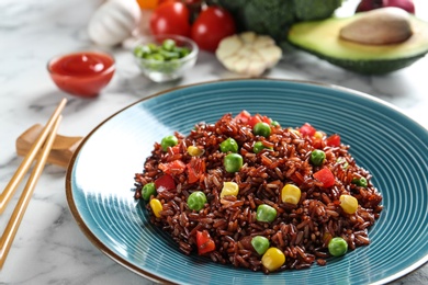 Photo of Plate of cooked brown rice with vegetables on table