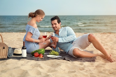 Beautiful young couple having picnic at sea beach