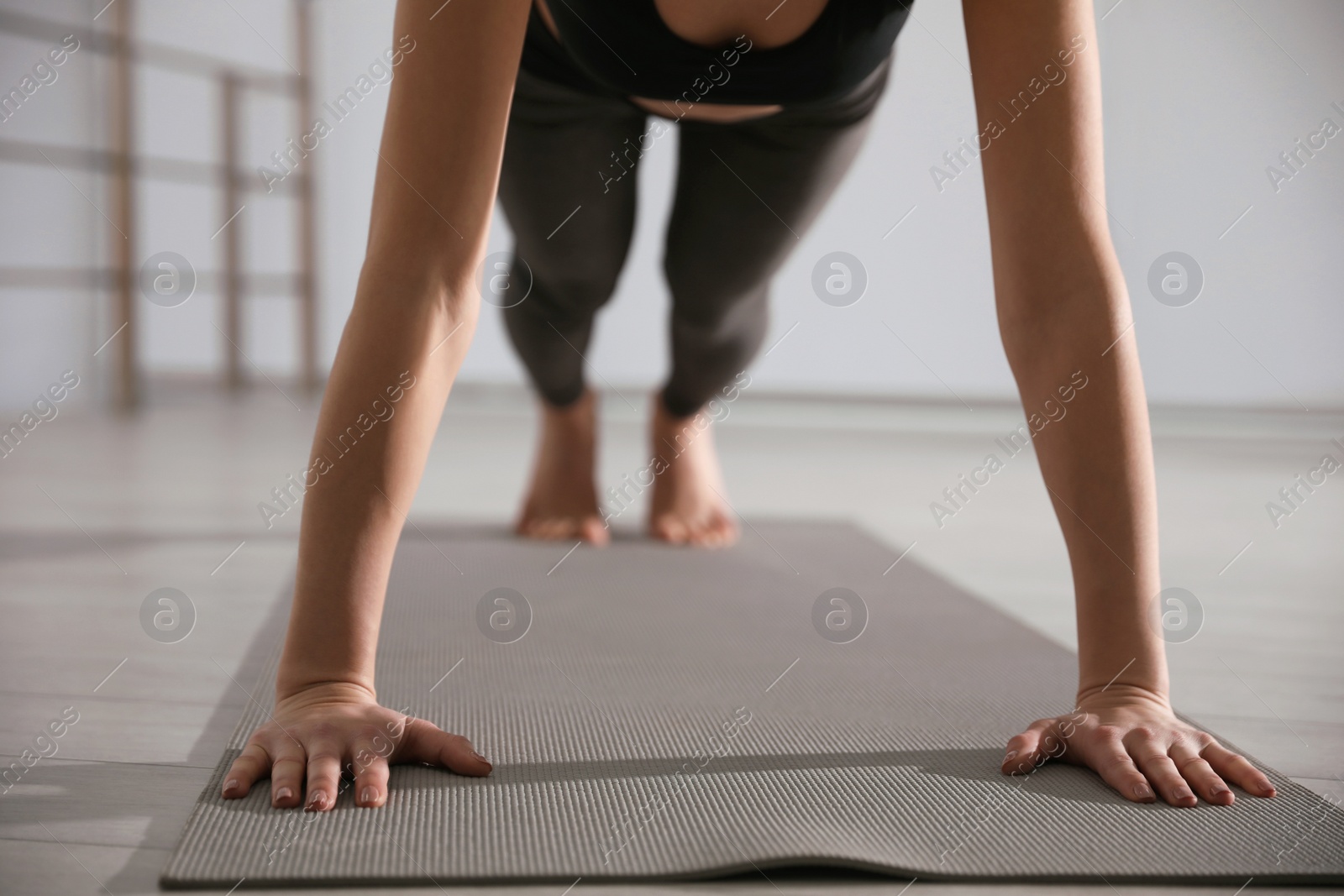 Photo of Young woman practicing plank asana in yoga studio, closeup. Phalankasana pose