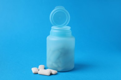 Jar with chewing gums on light blue background