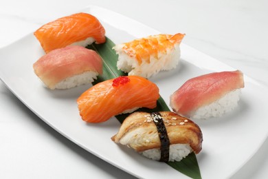 Plate with delicious nigiri sushi on white table, closeup