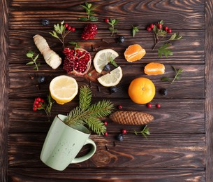 Photo of Cup and delicious immunity boosting ingredients for tea on wooden table, flat lay
