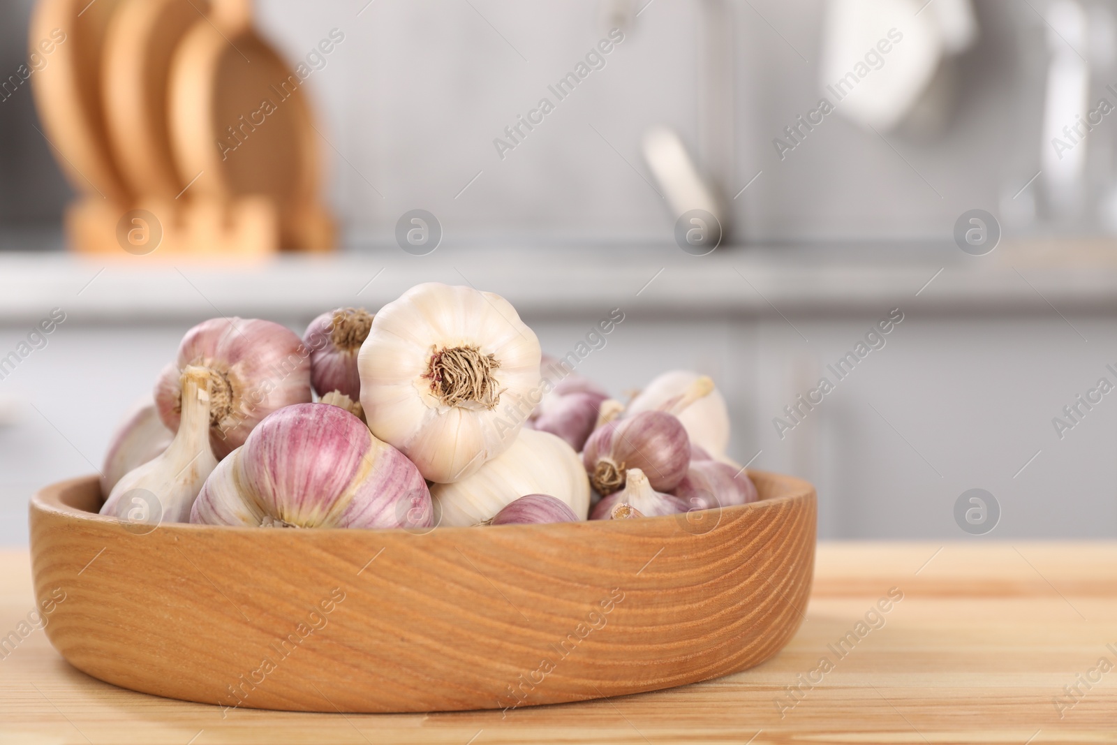 Photo of Bowl of fresh raw garlic on wooden table in kitchen