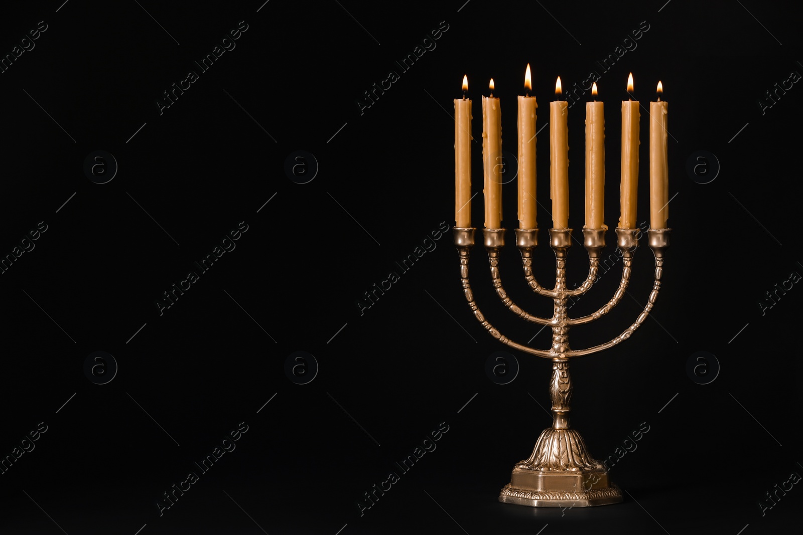 Photo of Golden menorah with burning candles on black background, space for text