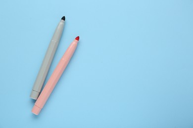 Photo of Bright markers on light blue background, flat lay. Space for text