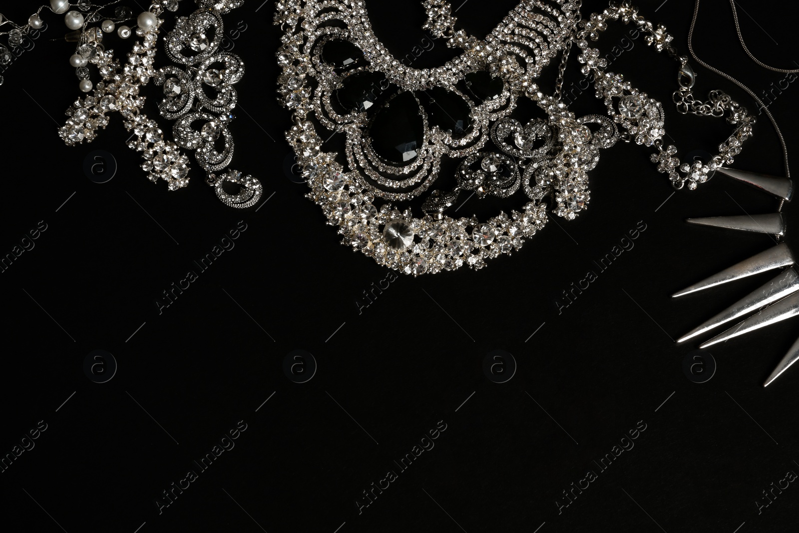 Photo of Different elegant jewelry on black background, top view. Space for text