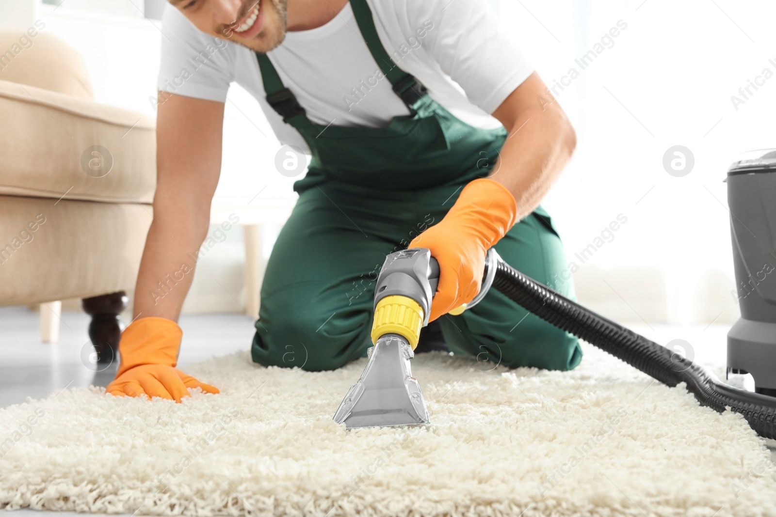 Photo of Janitor removing dirt from rug with carpet cleaner indoors, closeup