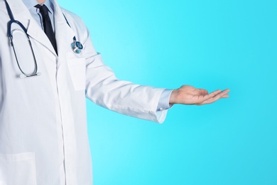 Male doctor offering helping hand on color background, closeup with space for text