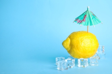 Photo of Creative composition with lemon, ice and cocktail umbrella on color background. Space for text