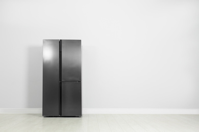 Photo of Modern refrigerator near light grey wall, space for text