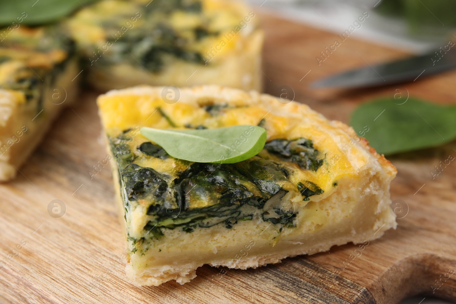 Photo of Piece of delicious pie with spinach on wooden board, closeup