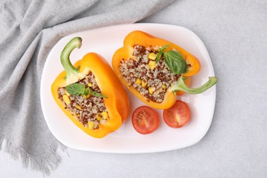 Photo of Quinoa stuffed bell pepper with basil and tomato on light table, top view