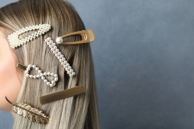 Young woman with beautiful hair clips on blue background, closeup. Space for text