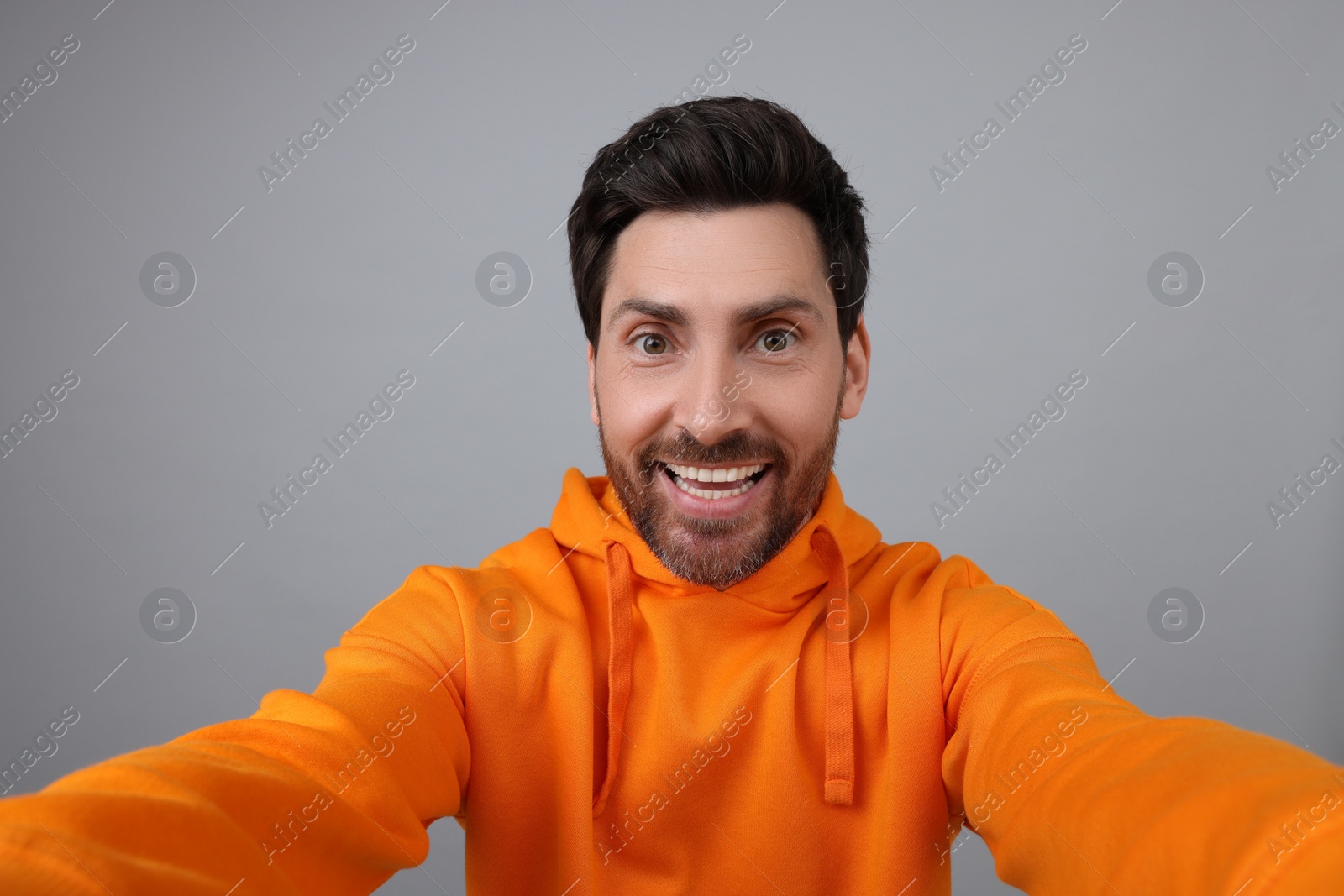 Photo of Smiling man taking selfie on grey background