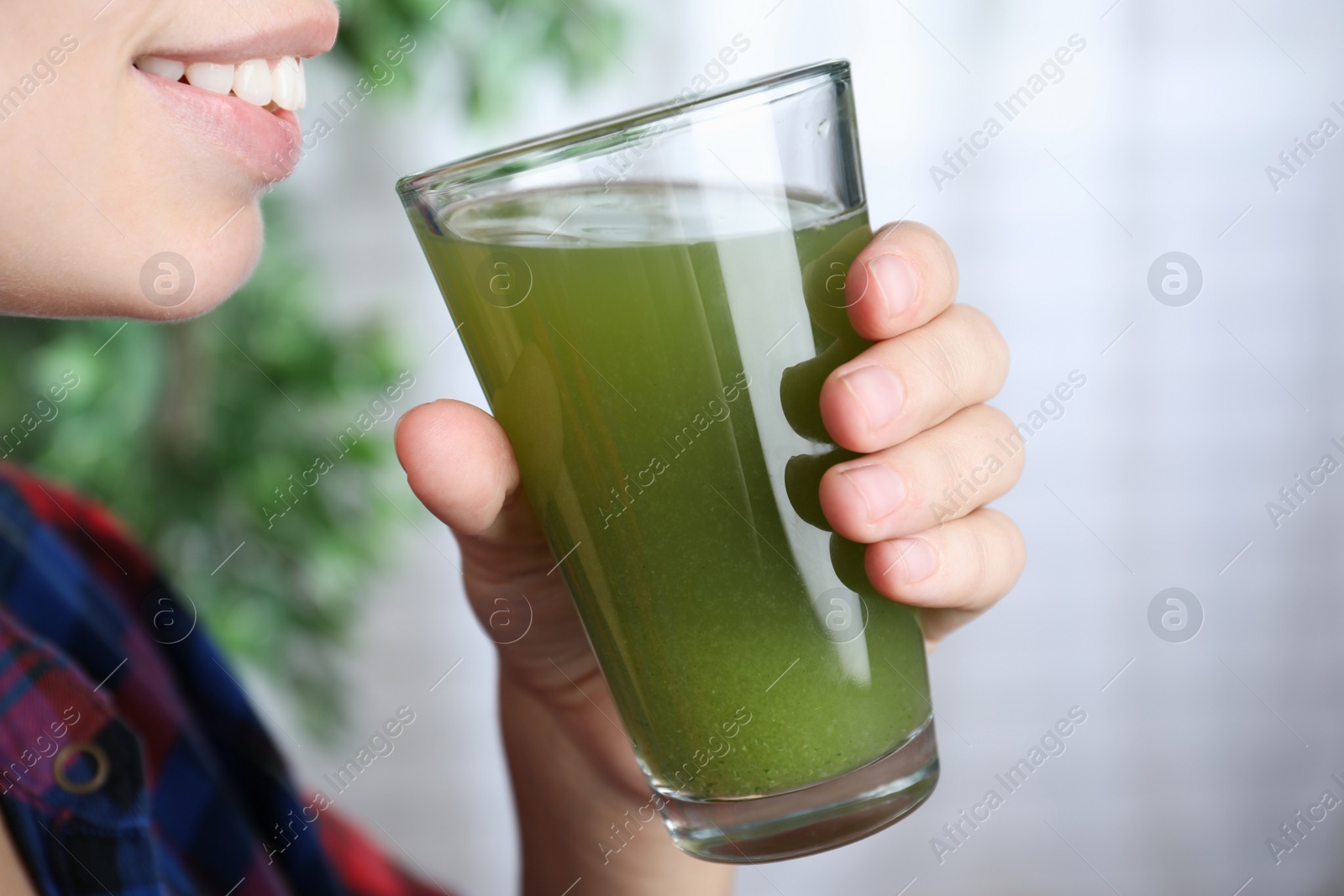 Photo of Woman holding glass with fresh celery juice indoors, closeup