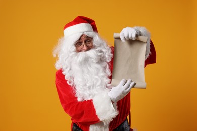 Photo of Merry Christmas. Santa Claus showing blank paper sheet on orange background