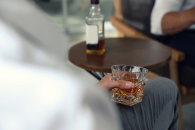 Man with glass of whiskey indoors, closeup view. Space for text