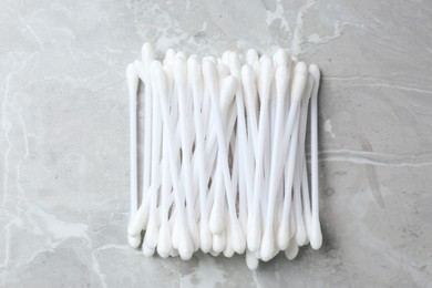 Many cotton buds on light grey marble table, flat lay