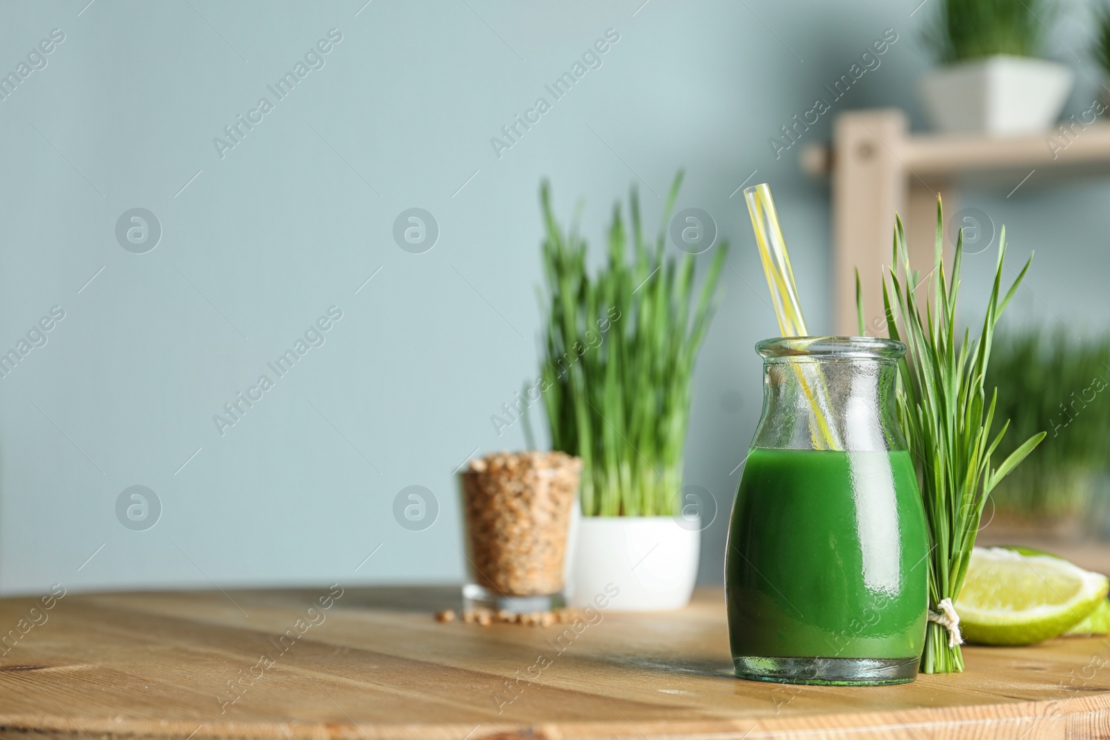 Bottle of juice and fresh wheat grass on table. Space for text Photo of Bottle of juice and fresh wheat grass on table. Space for text