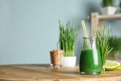Photo of Bottle of juice and fresh wheat grass on table. Space for text