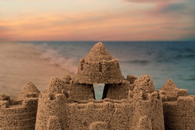 Image of Sand castle on ocean beach at sunset, closeup. Outdoor play