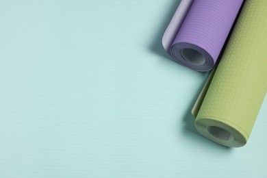 Photo of Two colorful wallpaper rolls on light turquoise sample, top view. Space for text