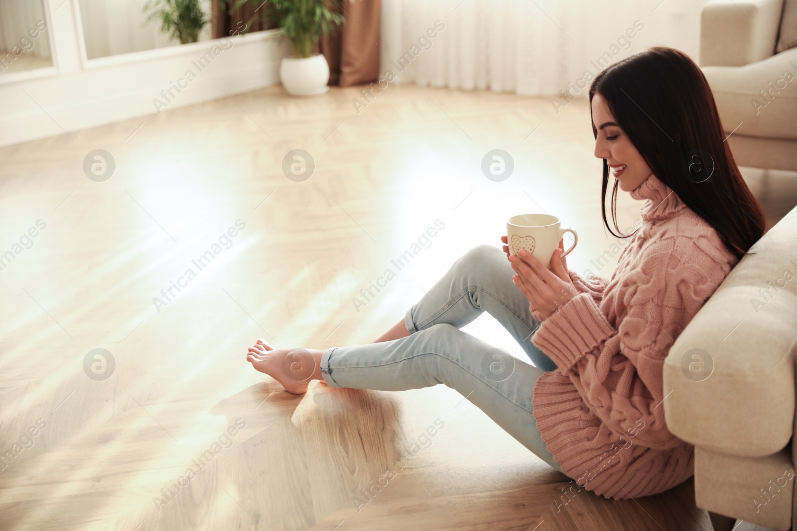 Photo of Woman sitting on warm floor in living room. Heating system