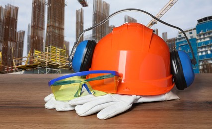 Image of Safety equipment and tools on wooden surface and blurred view of construction site