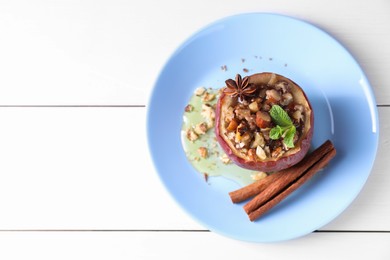 Photo of Tasty baked apple with nuts, honey, spices and mint on white wooden table, top view. Space for text