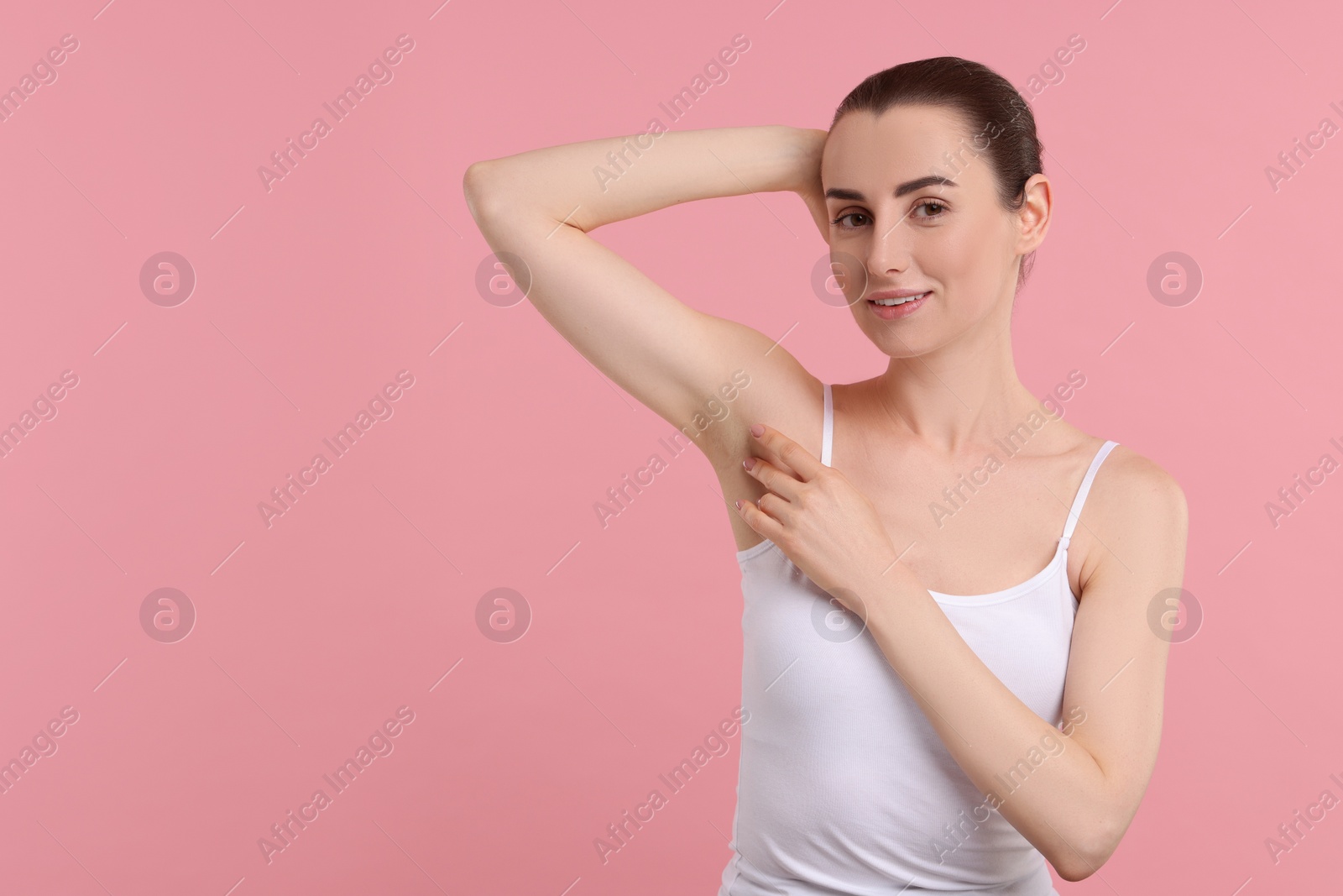 Photo of Beautiful woman showing armpit with smooth clean skin on pink background, space for text