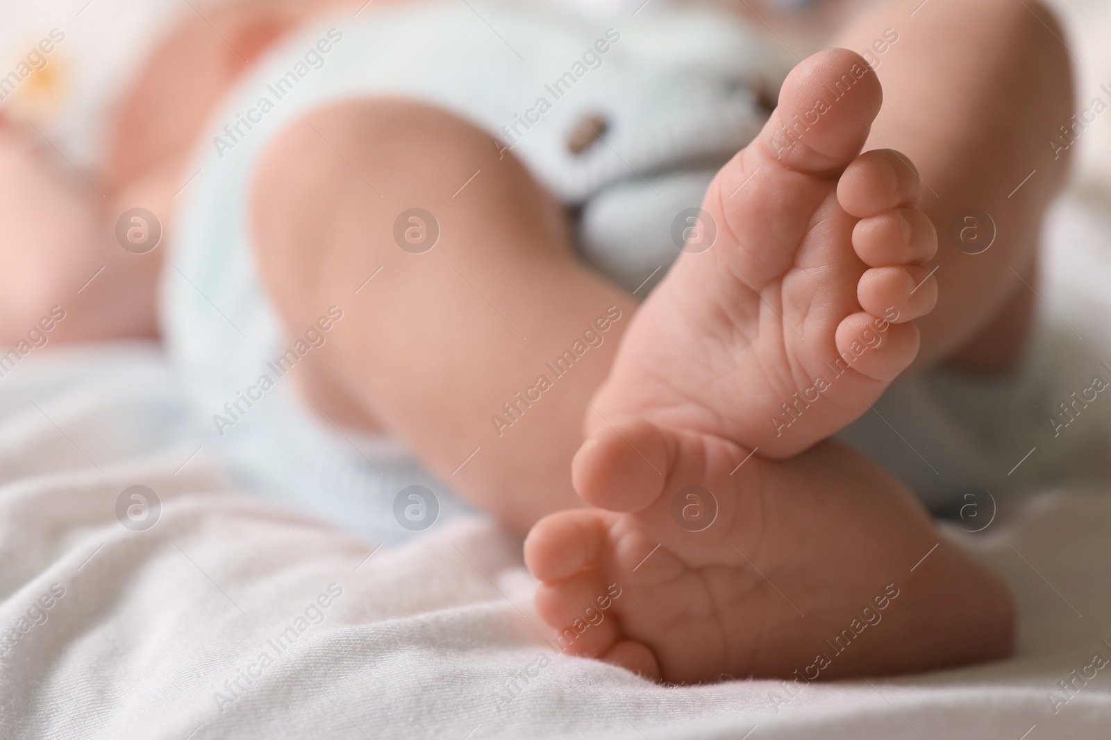 Photo of Cute newborn baby lying on bed, closeup of legs. Space for text