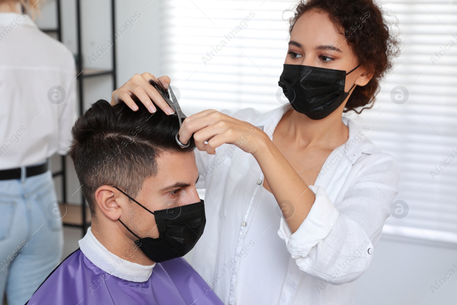 Photo of Professional stylist working with client in salon. Hairdressing services during Coronavirus quarantine