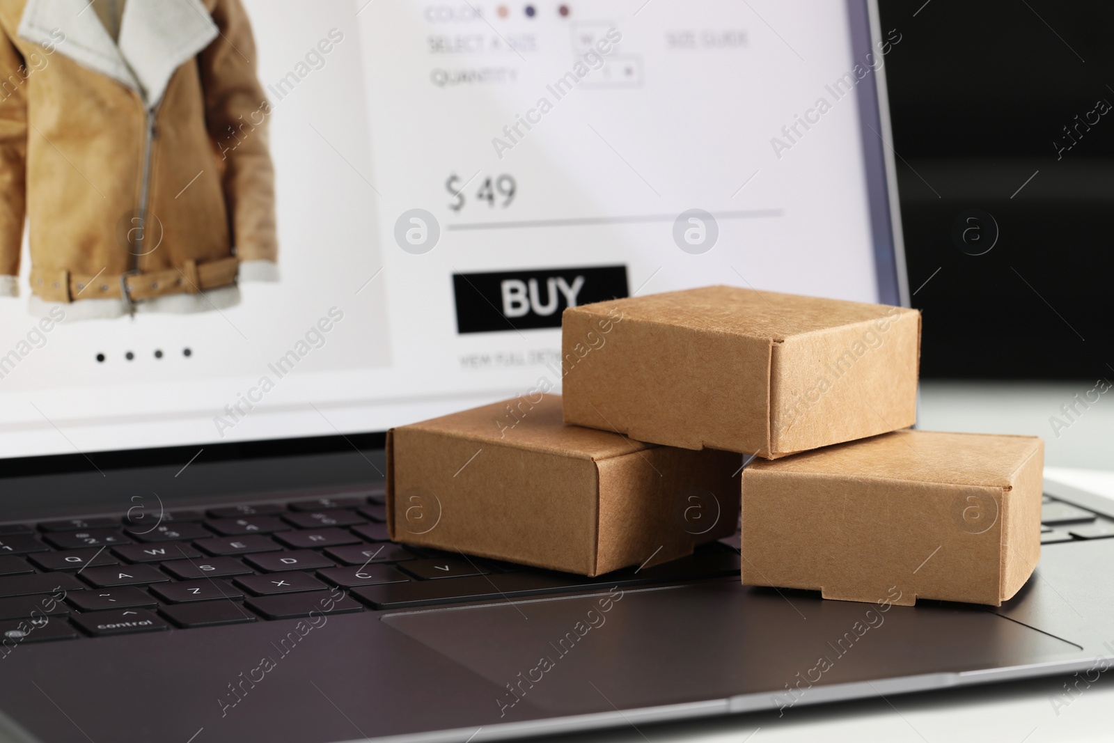 Photo of Online store. Small parcels on laptop, closeup