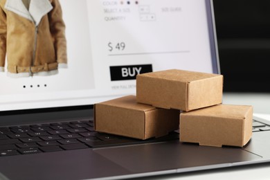 Photo of Online store. Small parcels on laptop, closeup