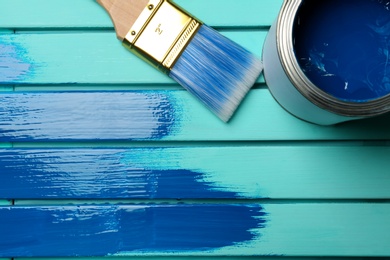 Photo of Paint can, brush and stroke on blue wooden background, top view. Space for text