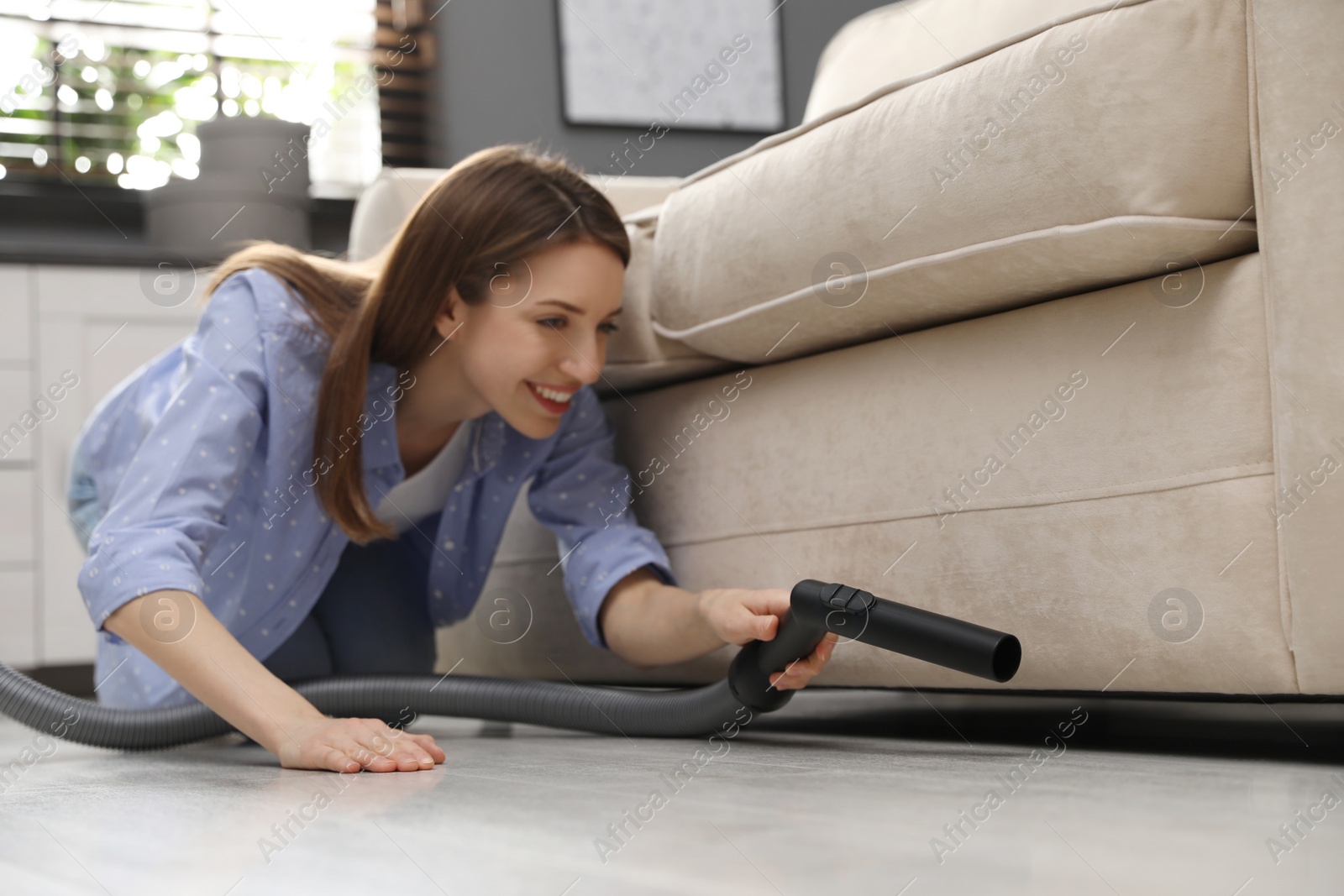 Photo of Young woman using vacuum cleaner at home