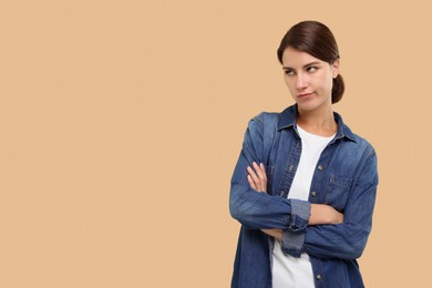 Photo of Resentful woman with crossed arms on beige background, space for text