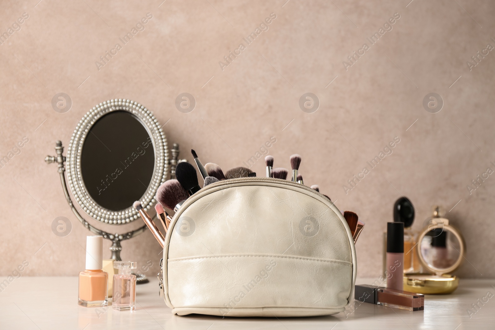 Photo of Luxury cosmetics and bag with makeup brushes on dressing table. Space for text