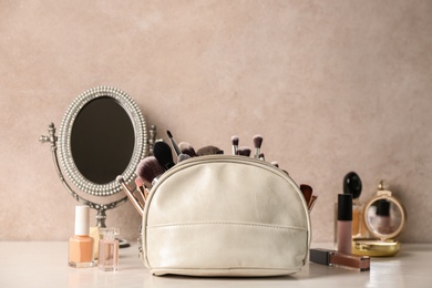 Photo of Luxury cosmetics and bag with makeup brushes on dressing table. Space for text