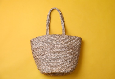 Photo of Stylish straw bag on yellow background, top view. Summer accessory
