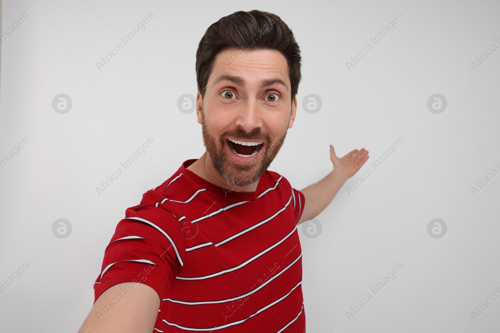 Photo of Smiling man taking selfie on white background