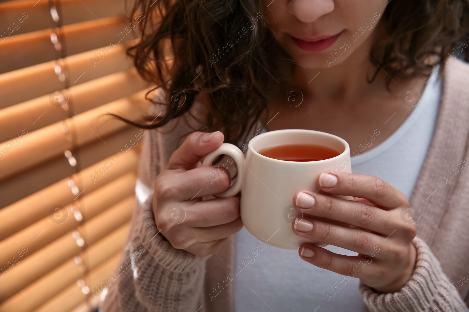 Photo of Woman with cup of hot tea indoors, closeup. Cozy home atmosphere