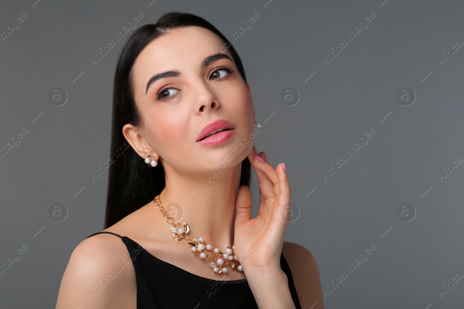 Photo of Beautiful young woman with elegant jewelry on dark grey background