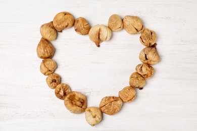 Photo of Heart shaped frame made of dried figs on wooden table, top view with space for text. Healthy fruit