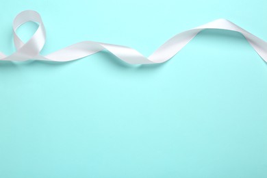 Photo of Beautiful white ribbon on light blue background, top view. Space for text