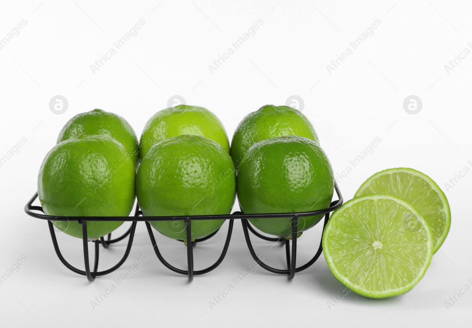 Photo of Fresh ripe limes and metal stand on white background