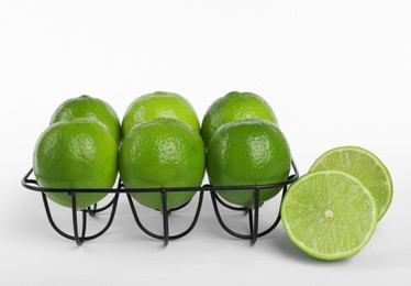 Photo of Fresh ripe limes and metal stand on white background