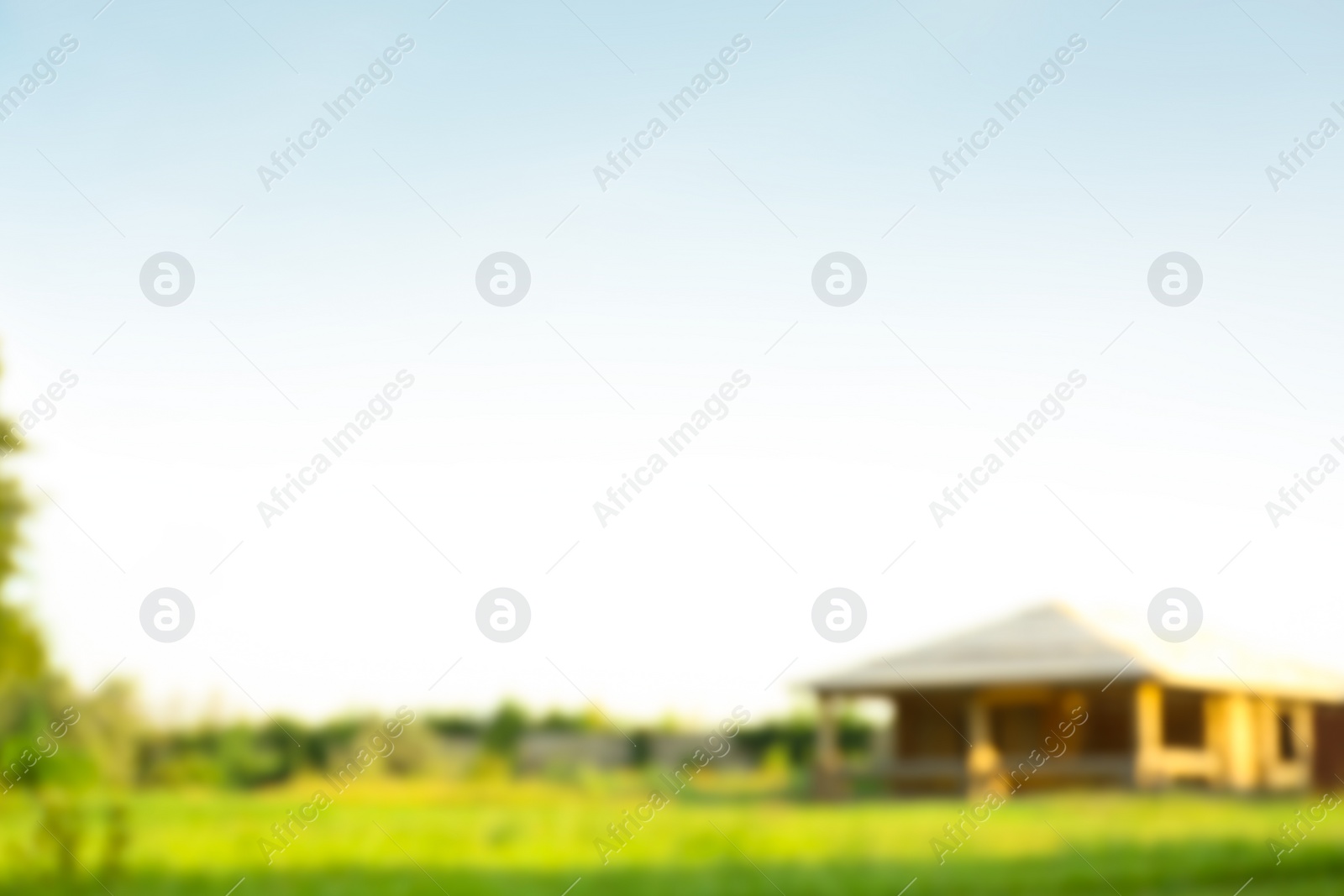 Photo of Blurred view of landscape with meadow and building on sunny day