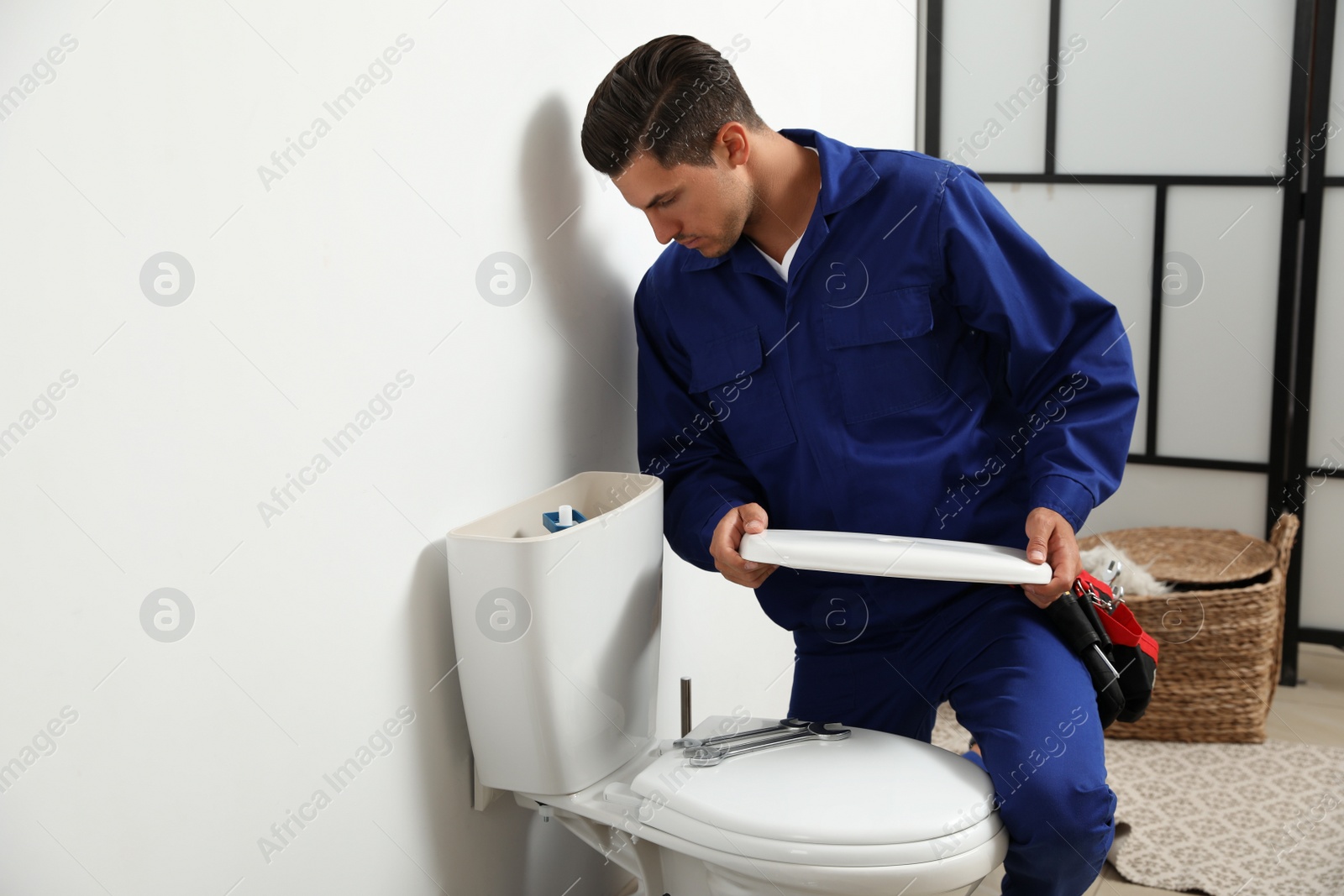 Photo of Professional plumber working with toilet bowl in bathroom