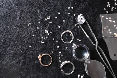 Photo of Flat lay composition with precious stones and jewelry tools on black leather background
